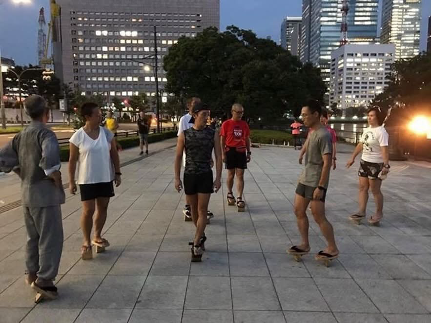 夕暮れの皇居周辺で、一本歯下駄を履いて練習する下駄練の参加者たち